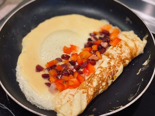 omelet with bacon and tomato fried in a pan