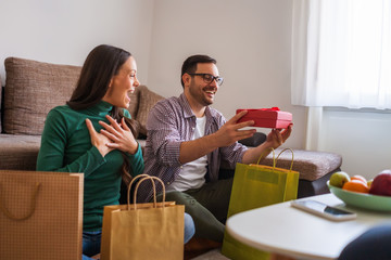 Happy couple is sharing gifts in their home.