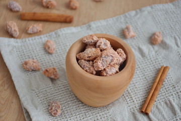 Candied almonds in wooden bowl with cinnamon on a wooden table