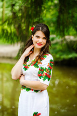 Beautiful girl in a bright traditional dress stands near a scaffold in the park