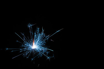 Fototapeta premium Sparkler in blue and white light on a black background