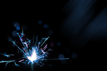 Sparkler in blue and white light on a black background