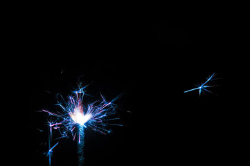 Obraz premium Sparkler in blue and white light on a black background