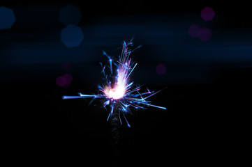 Sparkler in blue and white light on a black background