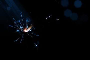 Obraz premium Sparkler in blue and white light on a black background