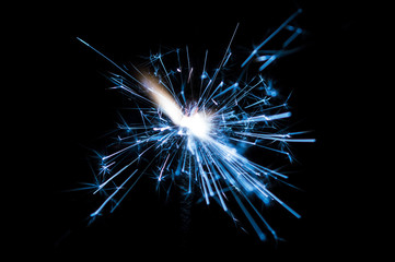 Sparkler in blue and white light on a black background