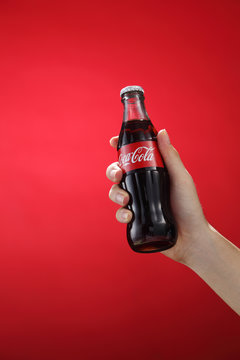 hand holding bottle of classic coca cola on the red background