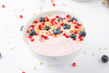 Fototapeta na wymiar Smoothie bowl with yogurt, granola, blueberries, pomegranate seeds and shredded coconut. Healthy breakfast.