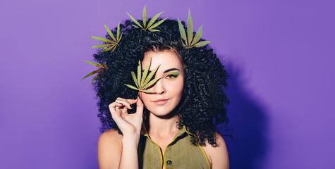 Mixed race woman with Afro-curls holding hemp Leaf. The concept of legalization of marijuana and...
