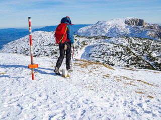Fototapeta na wymiar Mountaineer walking by the way sign at the top of the Peca mountain, Slovenia