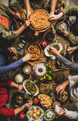Traditional Turkish family celebration dinner. Flat-lay of people feasting at table with Turkish salads, cooked vegetables, meze starters, borek pie and raki drink, top view. Middle Eastern cuisine