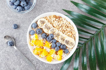 Healthy smoothie bowl with mango, blueberries, bananas, coconut, chia and granola. Healthy summer dessert.
