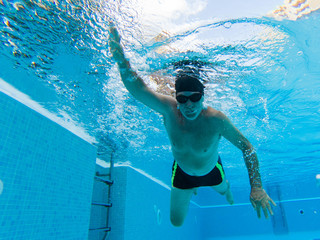 one active senior alone in the pool swimming and training to be healthy and a fitness man - summertime having fun at the swimming pool