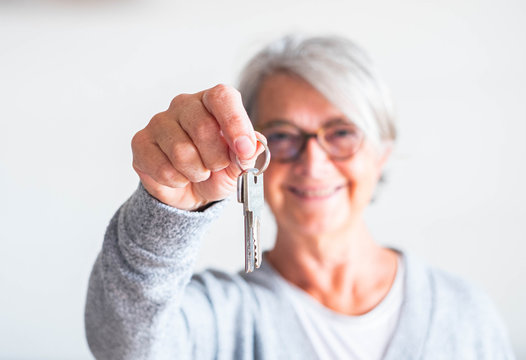 One Senior And Mature Woman Holding A Key Of A House Or Car - Seller Her Property To Someone Ready To Rent Or Buy