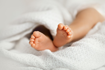 Adorable baby legs covered in a white blanket, maternity and babyhood concept