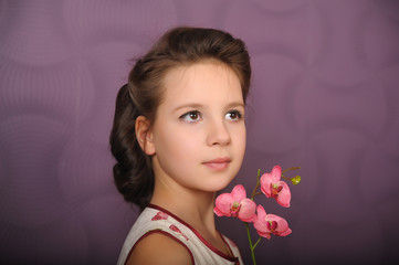 Obraz na płótnie Canvas happy child girl with big brown eyes, happy with an orchid in her hands