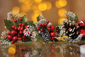 Branches with red berries and snowed corns toy on the yellow garland lights background. Christmas holiday and New Year decoration