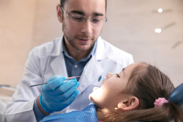 Young caucasian girl calm and happy visiting dentist's office for prevention and treatment of the oral cavity. Child and doctor while checkup teeth. Healthy lifestyle, healthcare and medicine concept.