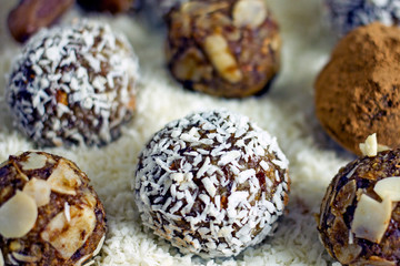 Raw Food Candy Balls. Handmade vegan sweets made of almonds, walnuts, dates, coconut and cocoa. Raw food candies in coconut flakes close-up. The concept of healthy vegan sweets, sugarless candie