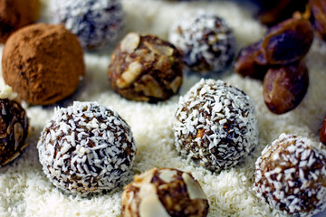 Raw Food Candy Balls. Handmade vegan sweets made of almonds, walnuts, dates, coconut and cocoa. Raw food candies in coconut flakes close-up. The concept of healthy vegan sweets, sugarless candie