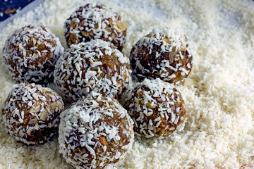 Raw Food Candy Balls. Handmade vegan sweets made of almonds, walnuts, dates, coconut and cocoa. Raw food candies in coconut flakes close-up. The concept of healthy vegan sweets, sugarless candie