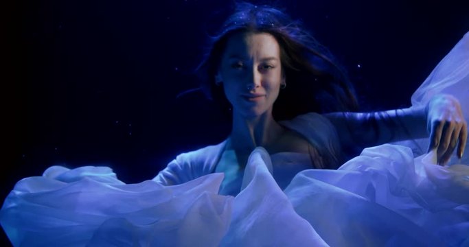 beautiful underwater queen is swimming in deepness of ocean, looks at camera
