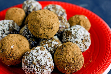 Raw food candy. Handmade vegan sweets made from almonds, walnuts, dates, raisins, coconut and cocoa. Raw food candies in coconut and cocoa close-up. Healthy vegan sweets concept.