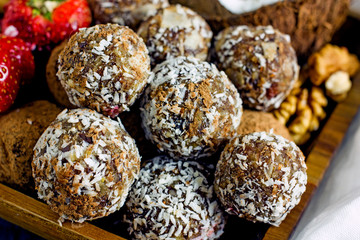 Raw food candy. Handmade vegan sweets made from almonds, walnuts, dates, raisins, coconut and cocoa. Raw food candies in coconut and cocoa close-up. Healthy vegan sweets concept.