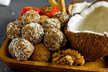 Raw food candy. Handmade vegan sweets made from almonds, walnuts, dates, raisins, coconut and cocoa. Raw food candies in coconut and cocoa close-up. Healthy vegan sweets concept.