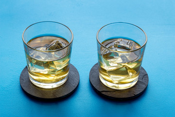 Whiskey with ice. To glasses of strong alcohol drink on blue background