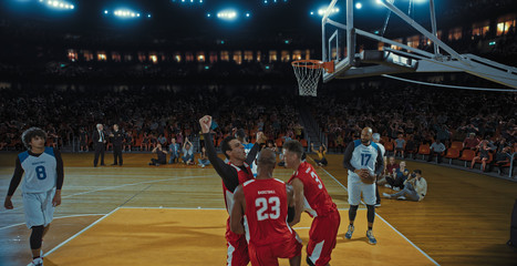 Basketball players on big professional arena during the game. Tense moment of the game. Celebration