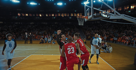 Basketball players on big professional arena during the game. Tense moment of the game. Celebration