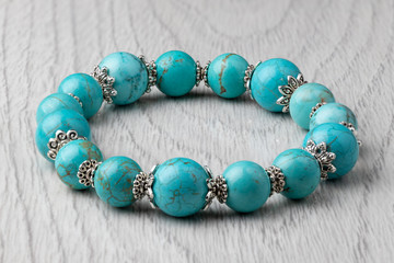 Bracelet made of natural turquoise stone on a light wooden background. Close-up