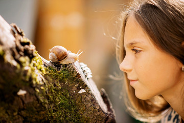 Joyful meeting of a little girl and a snail. Summer photo in the rain.