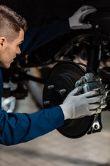 young mechanic fixing brake pad on disc brakes