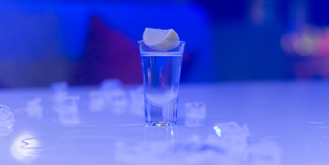 glasses of silver tequila, a slice of lime and pieces of ice on the table