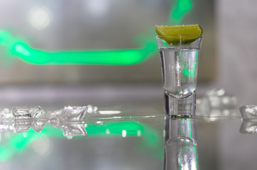 Naklejka na ściany i meble glasses of silver tequila, a slice of lime and pieces of ice on the table