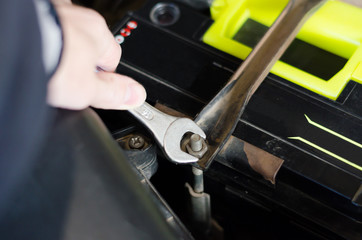 A car mechanic is repairing a car. Loosen the nuts on the parts