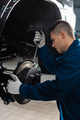 attentive mechanic adjusting brake caliper with screw driver