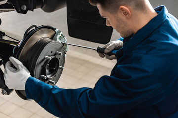 young mechanic adjusting brake caliper with screw driver