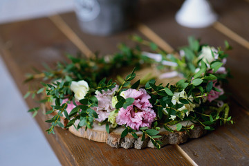 Beautiful wreath of spring flowers and green branches on a wooden round stand on the table.