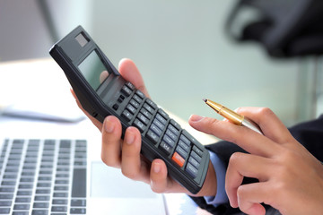 Businessman using a calculator to calculate the numbers in a office