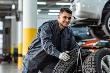 handsome, smiling mechanic holding new tire in workshop © LIGHTFIELD STUDIOS