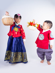 Asian little girl and boy wearing a Korean Traditional Hanbok dress in white background[The pattern on the fabric is Fu Lu Shou refers to the three Chinese deities]