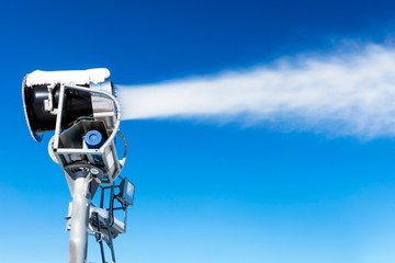 The work of snow cannons on a background of blue sky