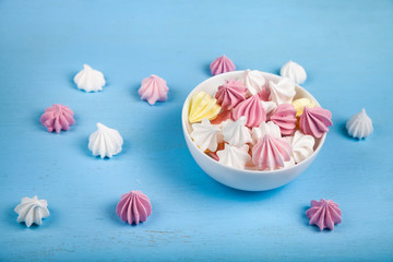 Meringue in a white bowl on a blue  wooden background.