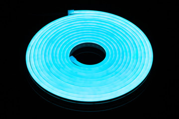 Flexible blue led tape neon flex in roll on black background.