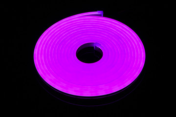 Flexible purple led tape neon flex in roll on black background.