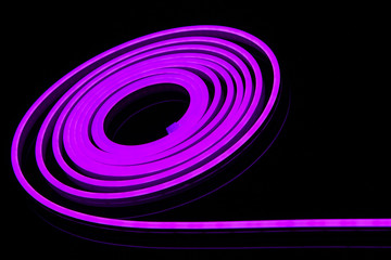 Flexible purple led tape neon flex in roll on black background.