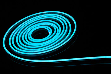 Flexible blue led tape neon flex in roll on black background.
